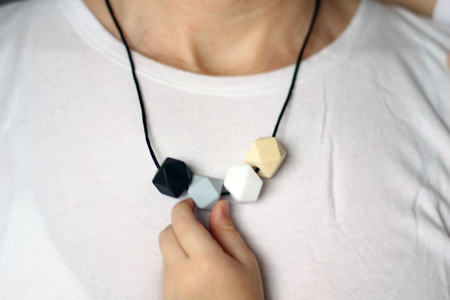Black - Fiddle Teething Necklace, natural wood & silicone with a little fiddling baby hand