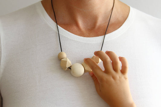 När börja med amningshalsband? - Baby exploring a nursing necklace during feeding